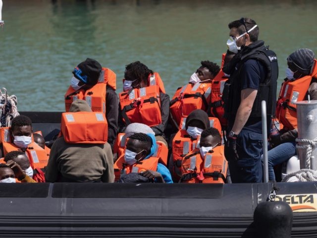 DOVER, ENGLAND - JUNE 24: Border Force officials guide newly arrived migrants to a holding