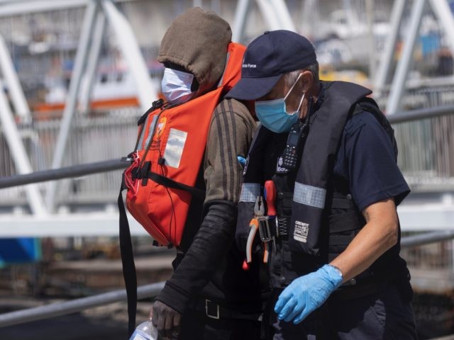 DOVER, ENGLAND - JUNE 24: Border Force officials guide newly arrived migrants to a holding