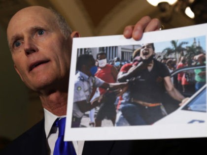 WASHINGTON, DC - JULY 13: U.S. Sen. Rick Scott (R-FL) holds up a photo from a recent protest in Cuba during a news briefing after a Senate Republican Policy Luncheon at the U.S. Capitol July 13, 2021 in Washington, DC. Senate GOPs gathered for the weekly policy luncheon to discuss …