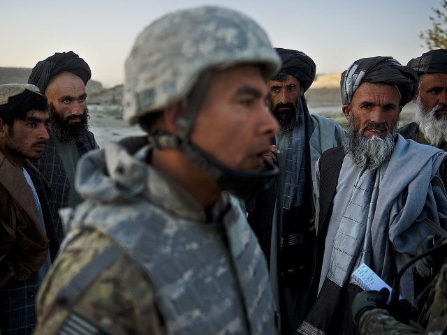 Afghan villagers look at a translator as US military soldiers from the 3rd platoon, C-company, 1-23 infantry (unseen) tend to a local Afghan man, who was shot because he was suspected of being an insurgent and planting a roadside bomb, in Genrandai village at Panjwai district, Kandahar on September 24, …