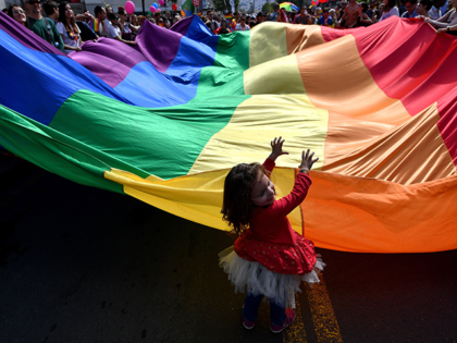 A child helps to wave a huge rainbow flag during the Gay Pride parade on September 17, 201