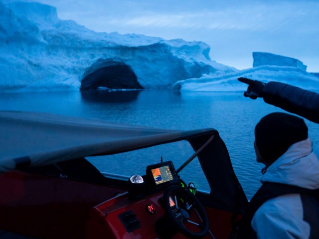 In this Aug. 16, 2019, photo, a boat navigates at night next to a large iceberg in eastern Greenland. Summer 2019 is hitting Greenland hard with record-shattering heat and extreme melt. Scientists estimate that by the end of the summer, about 440 billion tons (400 billion metric tons) of ice, …