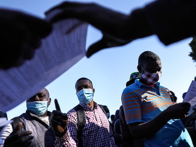 TIJUANA, MEXICO - FEBRUARY 19: People from Haiti who are seeking asylum in the United States wait for flyers explaining updated asylum policies outside the El Chaparral border crossing on February 19, 2021 in Tijuana, Mexico. Those seeking asylum have been waiting months and years in Tijuana and other locations …