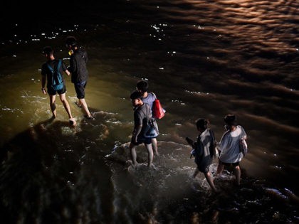 People wade through a flooded street following a heavy rain in Zhengzhou in China's Henan province on July 21, 2021. - At least 25 people have died including a dozen passengers trapped in a flooded subway after torrential rains inundated central China, paralysing several cities and causing millions of dollars …