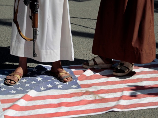 Houthi supporters step and walk on a representation of the U.S. flag during a demonstration outside the closed U.S. embassy against the United States over its decision to designate the Houthis a foreign terrorist organisation in Sanaa, Yemen, Monday, Jan. 18, 2021. (AP Photo/Hani Mohammed)