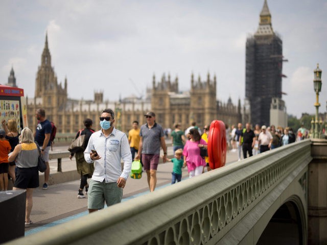Pedestrians, some wearing face masks cross Westminster Bridge with Elizabeth Tower, better