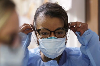 Respiratory therapist Lee Philips pulls on a second mask over her N95 mask before adding a face shield as she gets ready to go into a patient's room in the COVID-19 Intensive Care Unit at Harborview Medical Center, Friday, May 8, 2020, in Seattle. Data from COVID-19 projection models show …