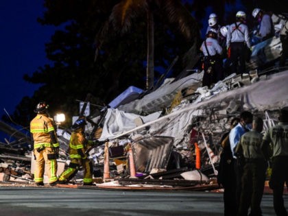 Search and Rescue personnel work as Miami Dade firefighters spray waterat a partial collapse building in Surfside, Miami Beach, on June 24, 2021. - A high-rise oceanfront apartment block near Miami Beach partially collapsed early Thursday, killing at least one person and leaving 99 unaccounted for, with fears the toll …