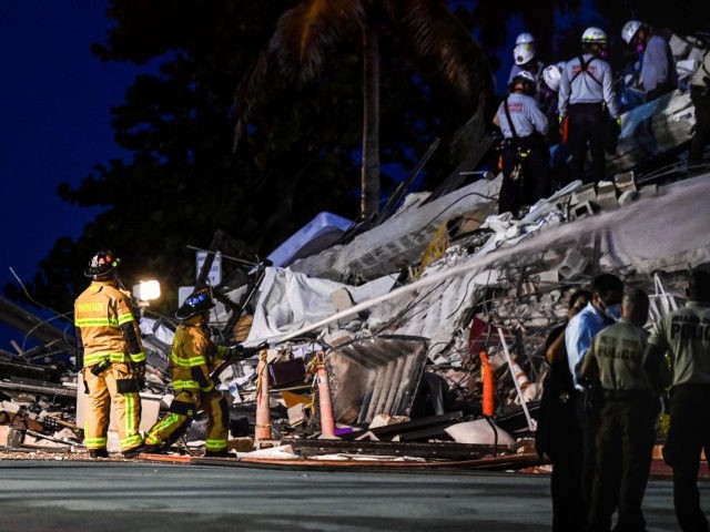 Search and Rescue personnel work as Miami Dade firefighters spray waterat a partial collapse building in Surfside, Miami Beach, on June 24, 2021. - A high-rise oceanfront apartment block near Miami Beach partially collapsed early Thursday, killing at least one person and leaving 99 unaccounted for, with fears the toll …