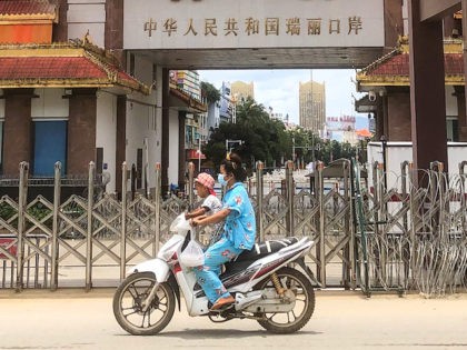 A woman rides a scooter with a child past the China-Myanmar border gate in Muse in Shan state on July 5, 2021, as the Chinese city of Ruili near the border with Myanmar imposed a lockdown and started mass testing after three Covid-19 coronavirus cases were reported on Monday. (Photo …