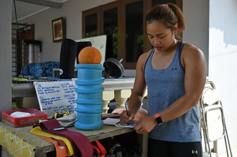 This picture taken on May 21, 2021 shows Olympic weightlifter Hidilyn Diaz of the Philippines writing notes during a training session in Jasin in the Malaysian city of Malacca. - Filipina weightlifter Hidilyn Diaz, who took silver at Rio 2016, has been stuck in Malaysia since February last year because of the coronavirus pandemic but has remained determined to realise her dream of becoming the first Olympic gold medal winner from the Philippines. - To go with 'OLY-2020-2021-WEIGHTLIFTING-PHILIPPINES,INTERVIEW' (Photo by Mohd RASFAN / AFP) / To go with 'OLY-2020-2021-WEIGHTLIFTING-PHILIPPINES,INTERVIEW' (Photo by MOHD RASFAN/AFP via Getty Images)