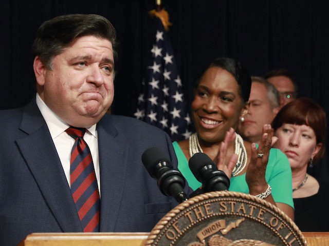 Gov. J.B. Pritzker takes in the applause before signing the state budget and legislation related to a graduated income tax in Illinois, during a bill signing Wednesday, June 5, 2019 at the Thompson Center in downtown Chicago. Applauding Pritzker is Lt. Gov. Juliana Stratton. (AP Photo/Amr Alfiky)