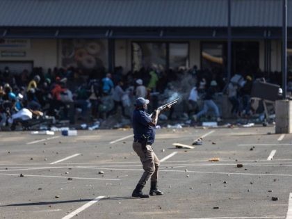 TOPSHOT - A member of the South African Police Services (SAPS) fires rubber bullets at rioters looting the Jabulani Mall in Soweto, southwest of Johannesburg, on July 12, 2021. - South Africa said it was deploying troops to two provinces, including Johannesburg, after unrest sparked by the jailing of ex-president …