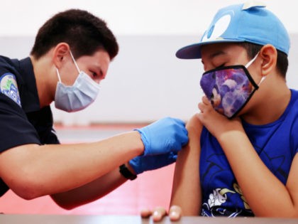 WINNETKA, CALIFORNIA - JULY 06: EMT Quentin Scarborough applies an adhesive bandage after administering a vaccine dose to student Nathan Alex Perez during a pop-up COVID-19 vaccination clinic at James Jordan Middle School on July 6, 2021 in Winnetka, California. The clinic was hosted by the Fernandeno Tataviam Band of …