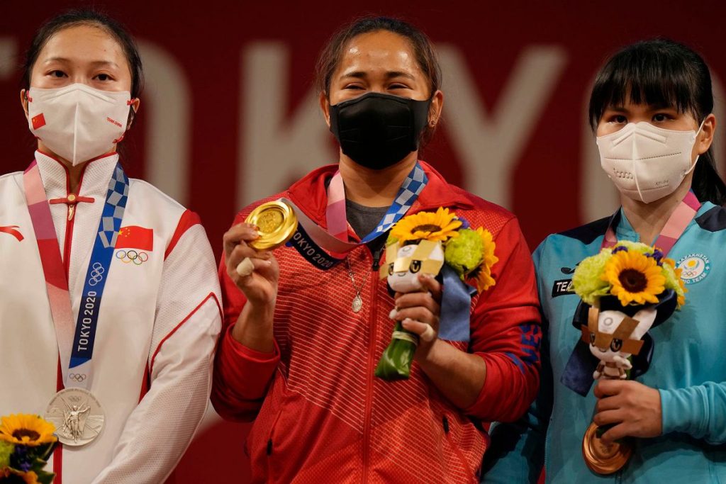 Gold medalist Hidilyn Diaz of Philippines, center, is flanked by silver medalist Liao Qiuyun of China, left and bronze medalist Zulfiya Chinshanlo of Kazakhstan, on the podium after the women's 55kg weightlifting event, at the 2020 Summer Olympics, Monday, July 26, 2021, in Tokyo, Japan. (AP Photo/Luca Bruno)