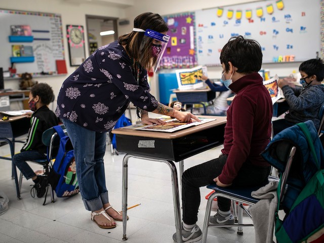STAMFORD, CONNECTICUT - SEPTEMBER 16: Teacher Elizabeth DeSantis, wearing a mask and face shield, helps a first grader during reading class at Stark Elementary School on September 16, 2020 in Stamford, Connecticut. Most students at Stamford Public Schools are taking part in a hybrid education model, where they attend in-school classes every other day and distance learn the rest. About 20 percent of students in the school district, however, are enrolled in the distance learning option due to coronavirus concerns. (Photo by John Moore/Getty Images)