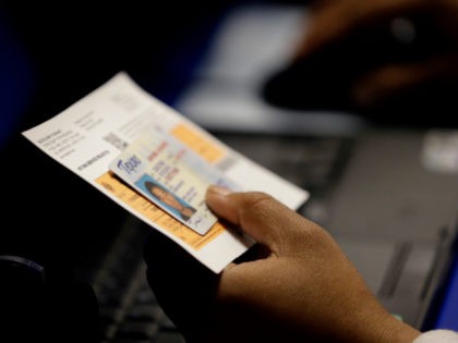 In this Feb. 26, 2014, file photo, an election official checks a voter's photo identification at an early voting polling site in Austin, Texas. A judge has ruled for a second time that Texas' strict voter ID law was intentionally crafted to discriminate against minorities. (AP Photo/Eric Gay, File)