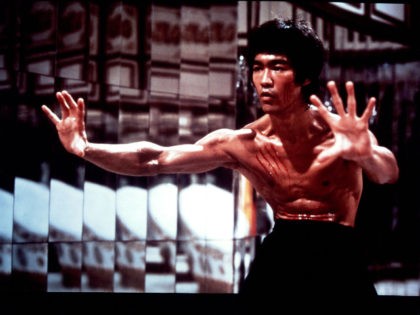 Bruce Lee with fresh scratch marks on his face and chest in a scene from the film 'En
