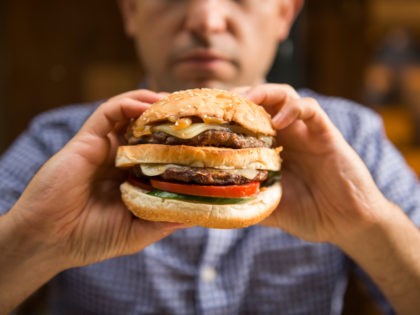 Man holding a big hamburger - stock photo Caucasian man holding a big hamburger