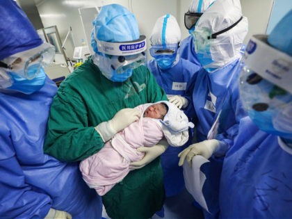 This photo taken on March 7, 2020 shows a medical staff member (C) holding a newborn after