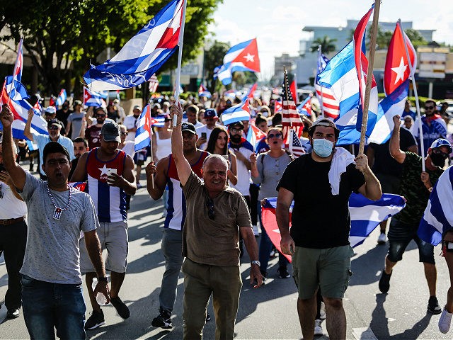 People hold Cuban and US flags as they march during a protest showing support for Cubans demonstrating against their government, in Miami, Florida on July 16, 2021. - Unprecedented anti-government protests broke out in Cuba on July 11, which the single-party state leadership blames on a Twitter campaign orchestrated by …