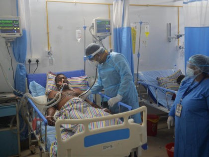 In this picture taken on June 1, 2021 a doctor (C) checks on a Covid-19 coronavirus patient at an Intensive Care Unit (ICU) of the Nightingale Hospital, on the outskirts of Siliguri. - Struggling with low pay, 24-hour shifts, and a severe shortage of staff and protective gear, doctors working …