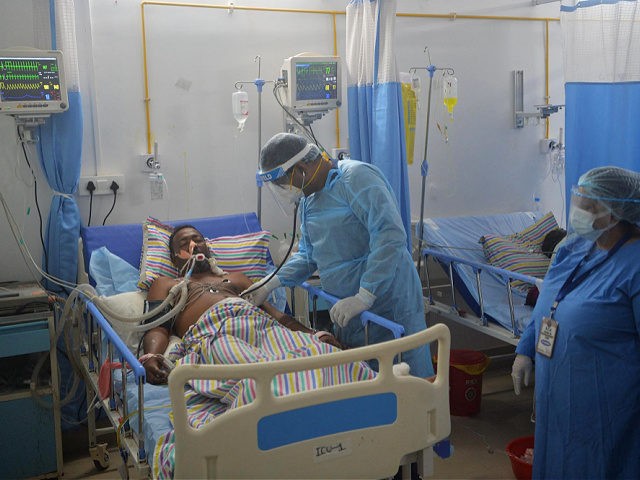 In this picture taken on June 1, 2021 a doctor (C) checks on a Covid-19 coronavirus patient at an Intensive Care Unit (ICU) of the Nightingale Hospital, on the outskirts of Siliguri. - Struggling with low pay, 24-hour shifts, and a severe shortage of staff and protective gear, doctors working …