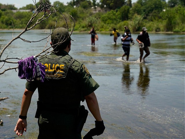 A Border Patrol agent watches as a group of migrants walk across the Rio Grande on their way to turn themselves in upon crossing the U.S.-Mexico border, Tuesday, June 15, 2021, in Del Rio, Texas. U.S. government data shows that 42% of all families encountered along the border in May hailed from places other than Mexico, El Salvador, Guatemala and Honduras â€” the traditional drivers of migratory trends. (AP Photo/Eric Gay)