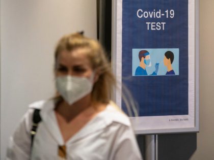 A passenger arriving from Istanbul and wearing a face mask, walks past a COVID-19 (novel coronavirus) test sign at the arrival hall of the Basel - Mulhouse Euroairport in Saint Louis, eastern France, on August 4, 2020. (Photo by SEBASTIEN BOZON / AFP) (Photo by SEBASTIEN BOZON/AFP via Getty Images)