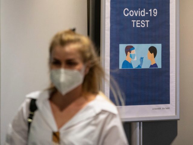 A passenger arriving from Istanbul and wearing a face mask, walks past a COVID-19 (novel c