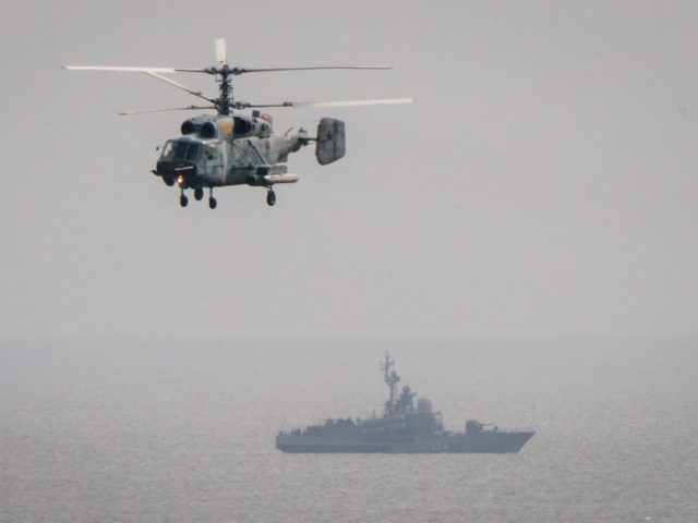 A military helicopter flies over a Russian battleship during the Vostok-2018 (East-2018) military drills at Klerka training ground on the Sea of Japan coast, outside the town of Slavyanka, some 100km south of Vladivostok, on September 15, 2018. (Photo by Mladen ANTONOV / AFP) (Photo credit should read MLADEN ANTONOV/AFP …