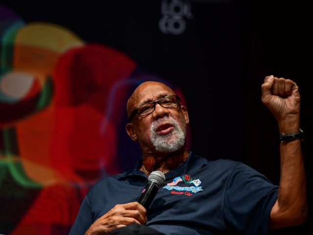 Former US track and field athlete and professional football player John Carlos, raises his fist as he speaks during a conference at the National University (Unam) in Mexico City, on September 24, 2018 - Tommie Smith had just turned 24, and John Carlos 23, when they raised their gloved fists …