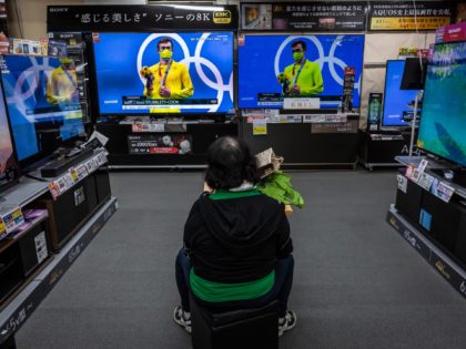 TOKYO, JAPAN - JULY 29: A woman watches Olympics games on televisions at an electronics retail store on July 29, 2021 in Tokyo, Japan. Fans have been barred from most Olympic events due to the Covid-19 pandemic, which also caused the Games' yearlong postponement. (Photo by Yuichi Yamazaki/Getty Images)