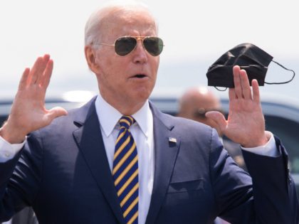 US President Joe Biden answers a question from the press as he holds a mask upon arrival o