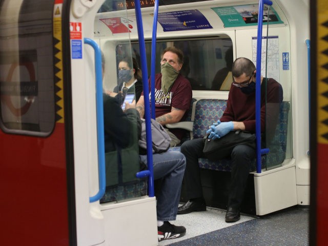 Commuters wear PPE (personal protective equipment), including a face mask as a precautiona