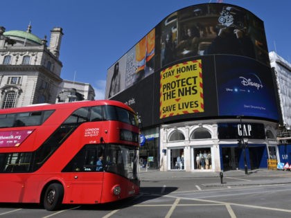 A government sign advising people to "Stay Home, Protect the NHS, Save Lives" is displayed on the advertising boards in Piccadilly Circus in the spring sunshine on the bank holiday Monday in London on April 13, 2020, as life in Britain continues over the Easter weekend, during the nationwide lockdown …