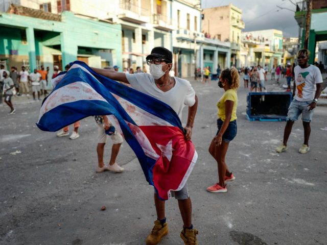 A man waves a Cuban flag during a demonstration against the government of Cuban President Miguel Diaz-Canel in Havana, on July 11, 2021. - Thousands of Cubans took part in rare protests Sunday against the communist government, marching through a town chanting "Down with the dictatorship" and "We want liberty." …