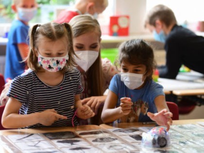 Pupils, wearing face masks, listen to their teacher during a summer project at the primary school 'Sonnenschule' in Beckum, western Germany, on July 6, 2021. - North-Rhine Westphalia's Minister of Education and Schools visits projects that have received funding from the state programme "Extra Time for Learning" during the summer. …