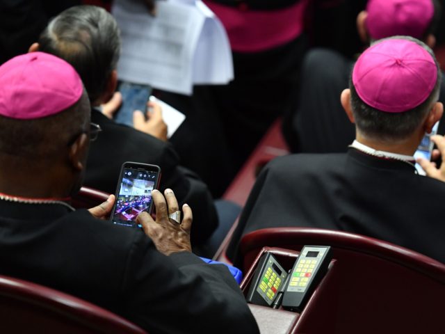 Bishops check their mobile phone prior to the start of the Synod of Bishops, focusing on Y