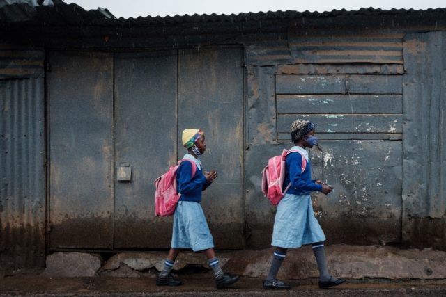 Students wearing masks walk to school in Kenya