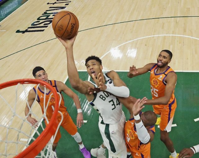 Milwaukee's Giannis Antetokounmpo shoots over Devin Booker, left, Chris Paul, right and Mi