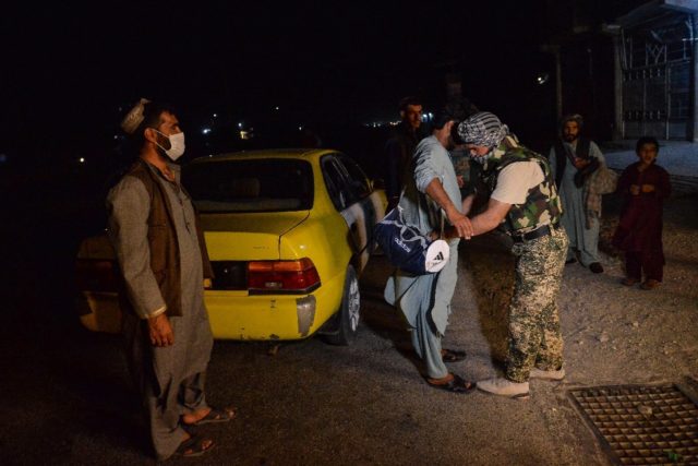 Afghan security force personnel searching a commuter at a checkpoint in Herat, western Afg