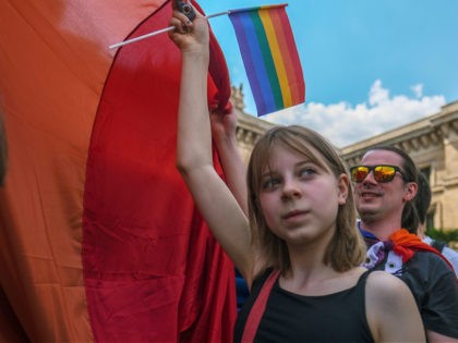 WARSAW, POLAND - JUNE 19: A young girl helps to hold a giant rainbow flag during the pride march on June 19, 2021 in Warsaw, Poland. According to ILGA-Europe's 2021 report, the status of LGBTQ rights in Poland is the worst among European Union countries. In 2020 several regions around …