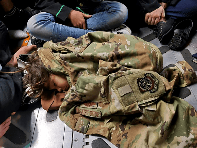 An Afghan child sleeps on the cargo floor of a U.S. Air Force C-17 Globemaster III, kept warm by the uniform of the C-17 loadmaster, during an evacuation flight from Kabul, Afghanistan, Aug. 15, 2021. Operating a fleet of Air National Guard, Air Force Reserve and Active Duty C-17s, Air Mobility Command, in support of the Department of Defense, moved forces into theater to facilitate the safe departure and relocation of U.S. citizens, Special Immigration Visa recipients, and vulnerable Afghan populations from Afghanistan. (U.S. Air Force Courtesy Photo)