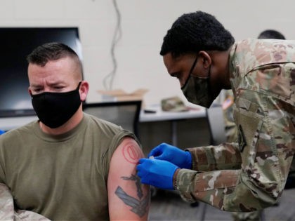 Maj. Michael Childress receives a bandage from Sgt. Christian Minor after being inoculated