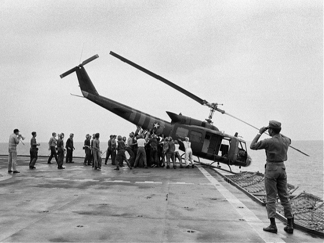 U.S. Navy personnel aboard the USS Blue Ridge push a helicopter into the sea off the coast of Vietnam in order to make room for more evacuation flights from Saigon, Tuesday, April 29, 1975. The helicopter had carried Vietnamese fleeing Saigon as North Vietnamese forces closed in on the capital. (AP Photo/Jacques Tonnaire)