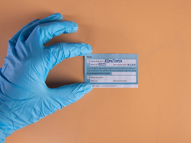 Hand wearing glove taking COVID-19 vaccination record card. Vaccine AstraZeneca