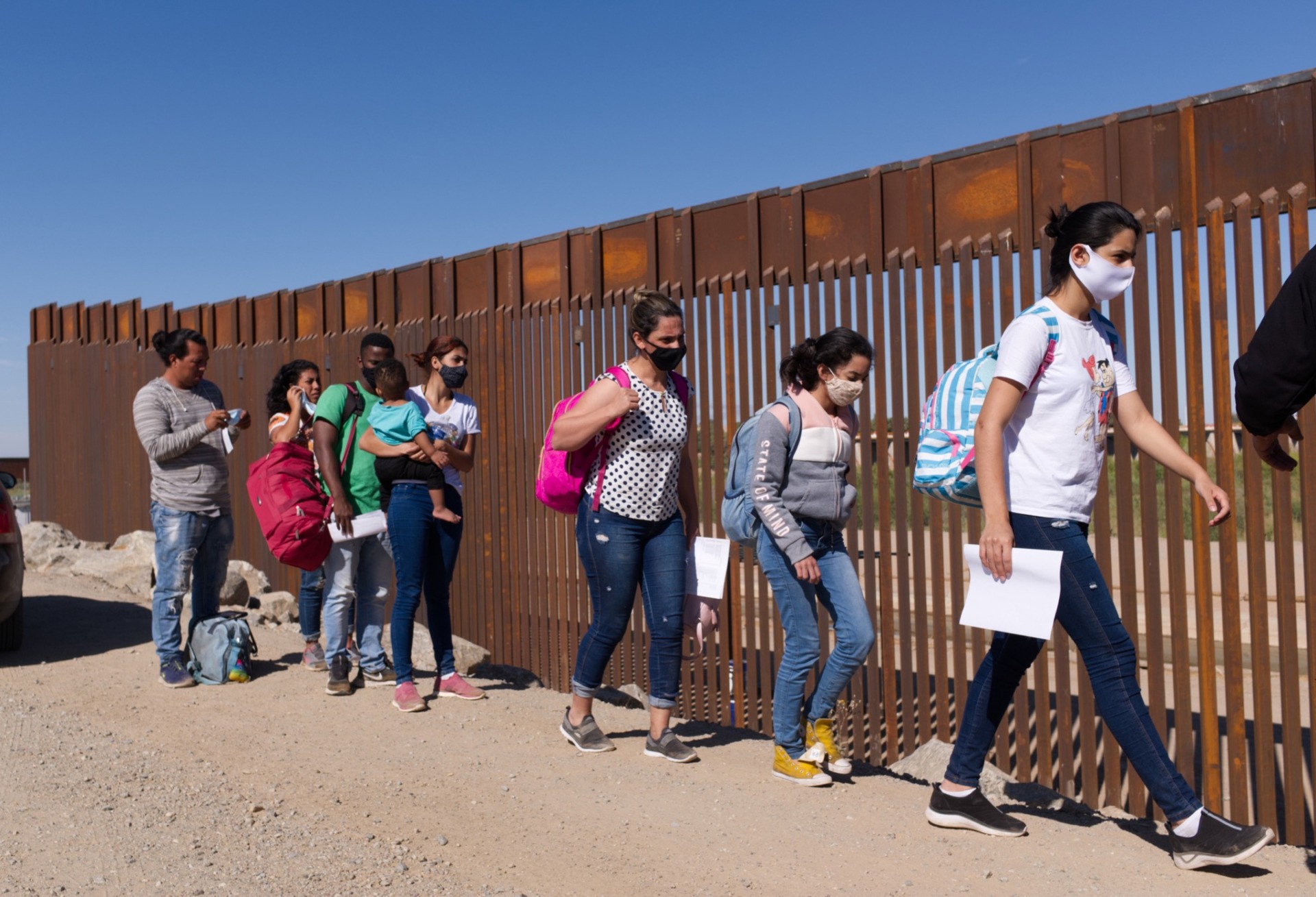 In this Tuesday, June 8, 2021, photo, a group of Brazilian migrants walk around a gap in the U.S.-Mexico border in Yuma, Ariz., seeking asylum in the United States after crossing over from Mexico. The Biden administration says it has identified more than 3,900 children separated from their parents at the U.S.-Mexico border under former President Donald Trump's "zero-tolerance" policy on illegal crossings. (AP Photo/Eugene Garcia)