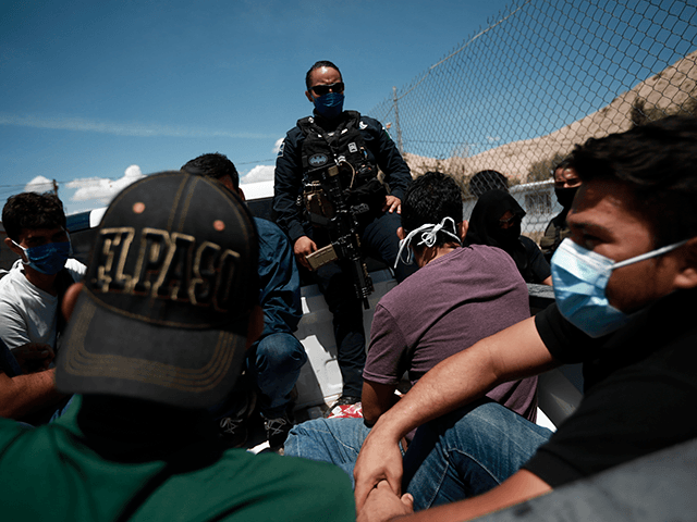 A police officer stands guard over a group of Central American migrants found in a house controlled by human smugglers, in Ciudad Juarez, Mexico, Saturday, July 3, 2021. Mexican police found dozens of migrants who smugglers were trying to enter into the United States undocumented. The migrants were transferred to …