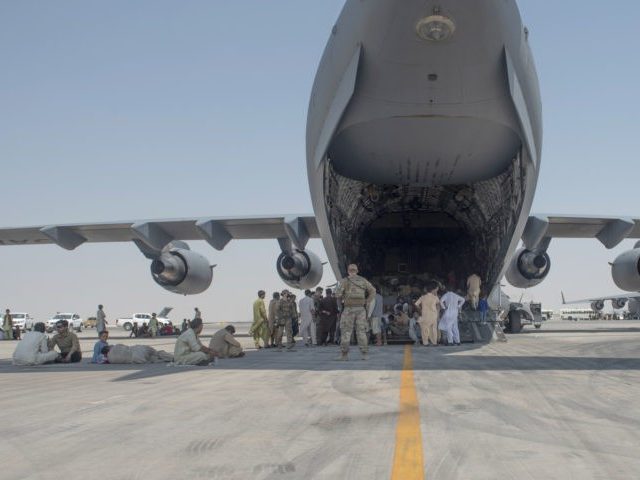 In this photo provided by the U.S. Air Force, evacuees wait under the wing of C-17 Globema